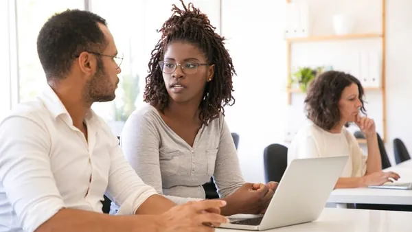 Business colleagues working on a laptop in an office — an article about cheap vs professional website development Nigeria