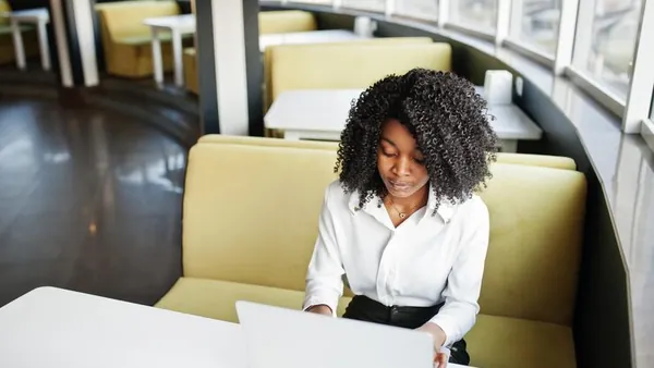An African businesswoman working on a laptop in a cafe — an article about automate repetitive business tasks with AI