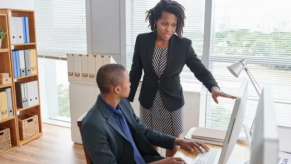 An African businesswoman on a call at a computer in an office — how to build a hotel booking app in Nigeria