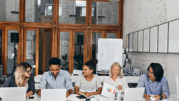 Business colleagues working on a laptop in a cafe — an article about connect AI to business APIs