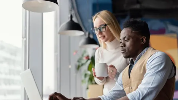 Business colleagues working on a laptop in an office — an article about logistics website design in Nigeria
