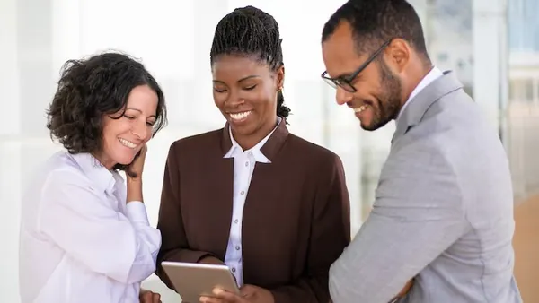 Business colleagues at work with a tablet in an office — an article about mobile app development in Abuja