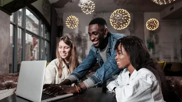 Business colleagues working on a laptop in an office — an article about signs your business needs business automation