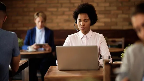 An African businesswoman working on a laptop in a cafe — an article about signs your business needs a new website