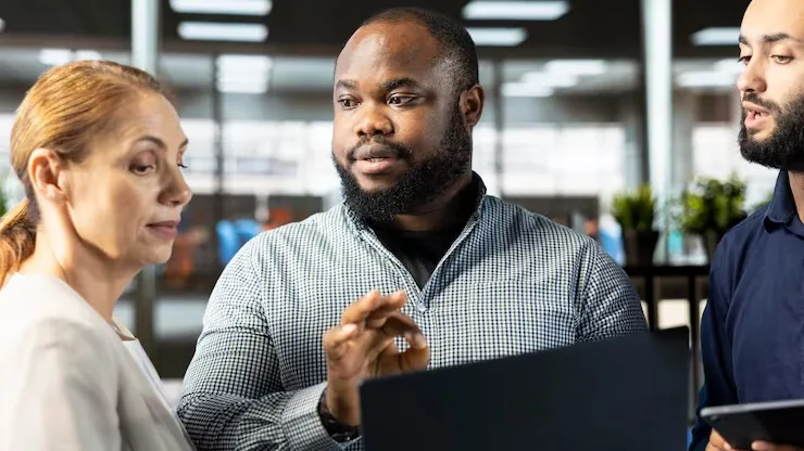 Business colleagues working on a laptop in an office — an article about website design for Nigerian real estate companies