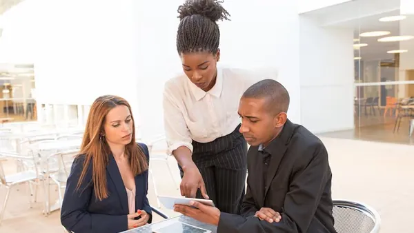 Business colleagues in a meeting with a tablet in an office — an article about app development contract